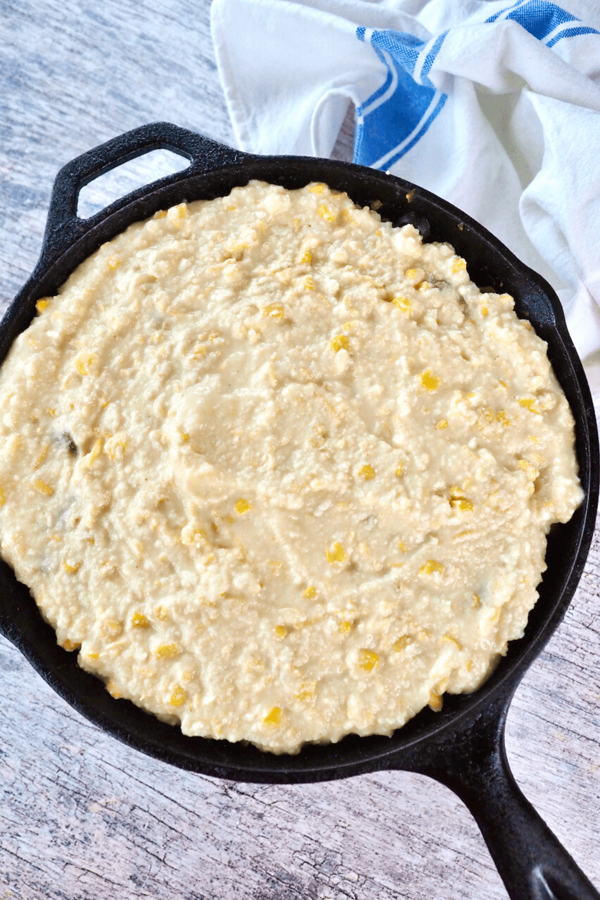 Spreading cornmeal crust on top to sides of tamale pie.