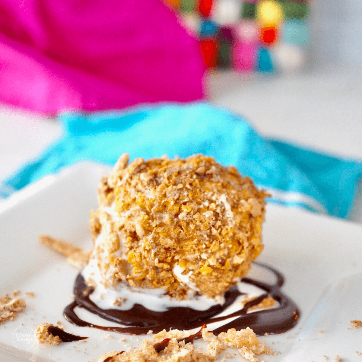 Fried ice cream on a plate drizzled with hot fudge. 