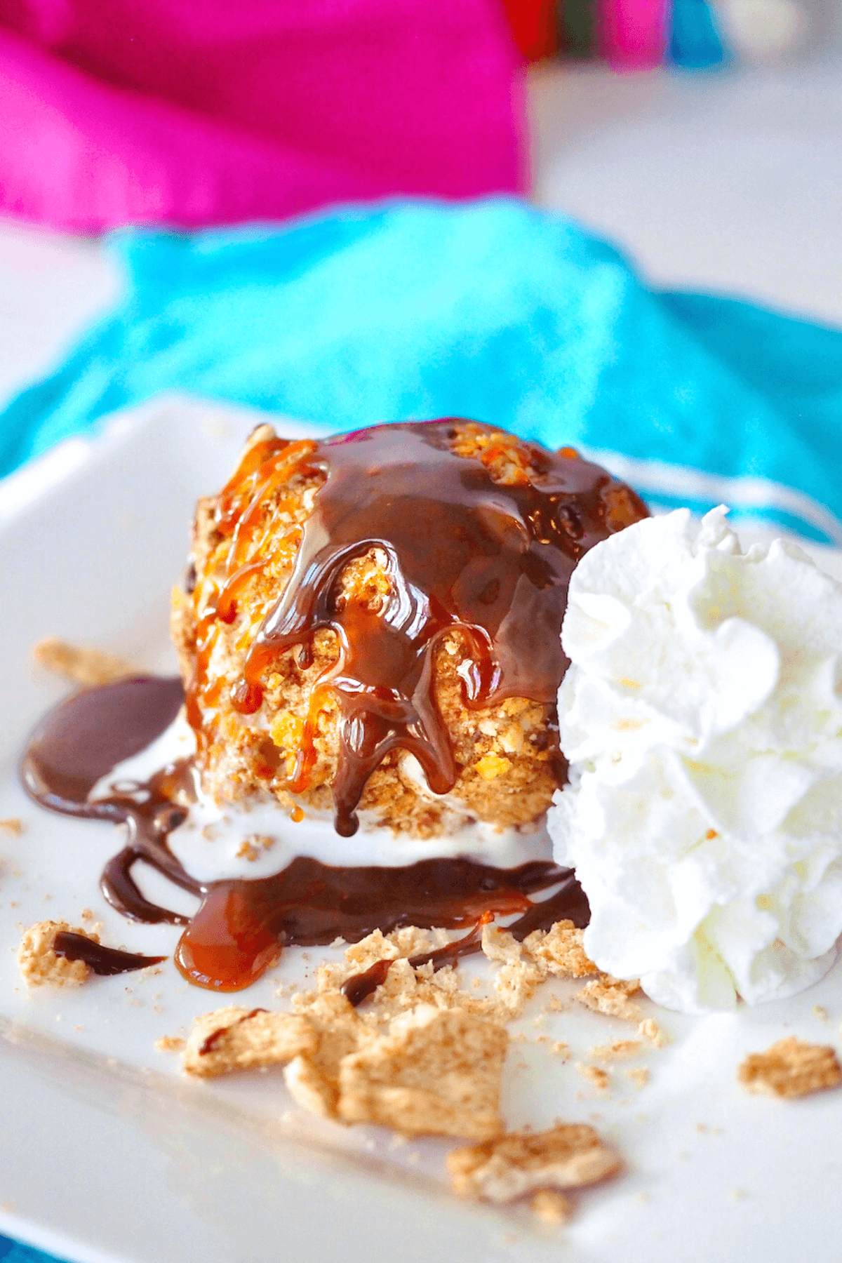 Easy Fried Ice Cream on plate drizzled with hot fudge and caramel sauce with whipped cream on the sides. 