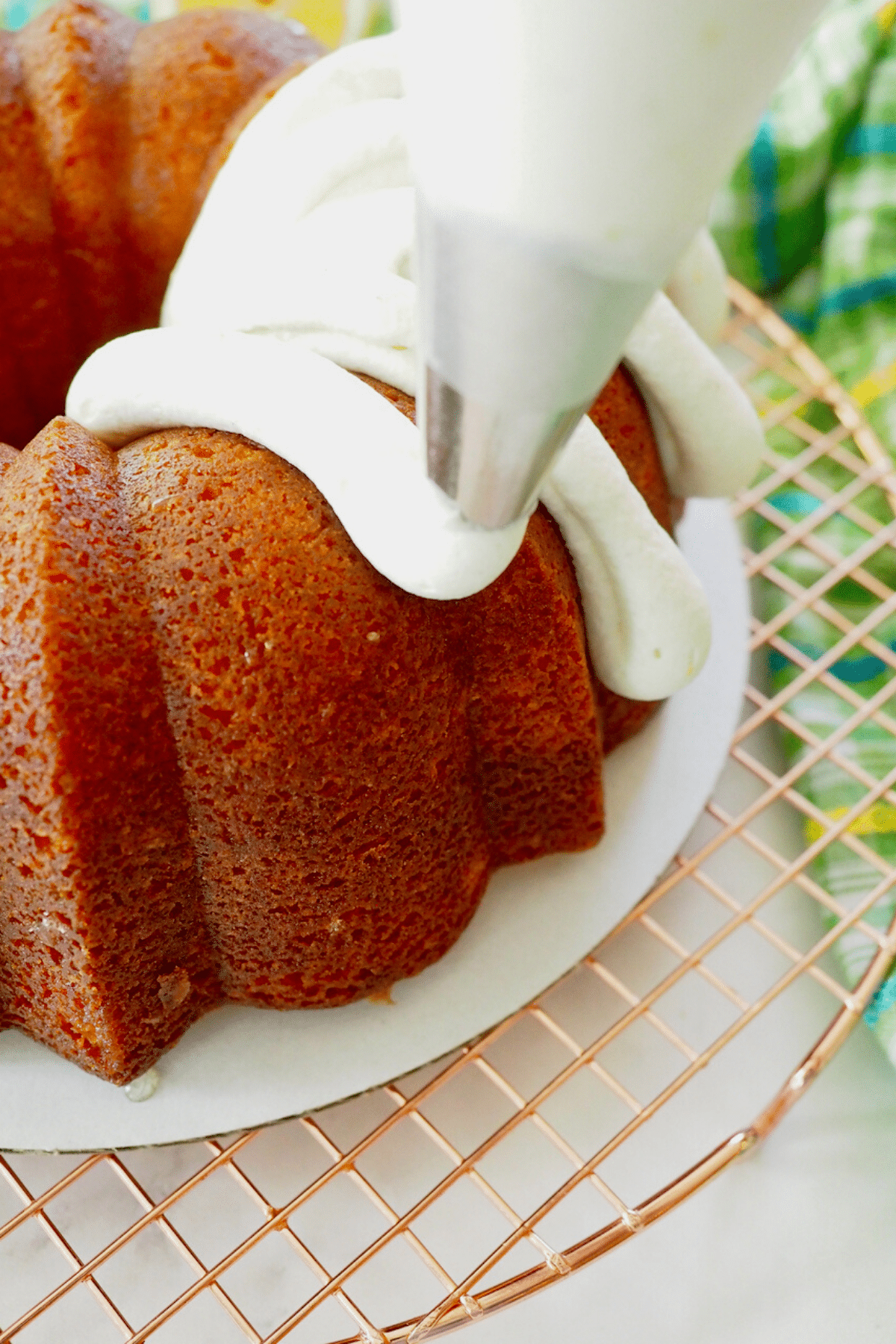 Piping fingers of frosting onto lemon bundt cake.