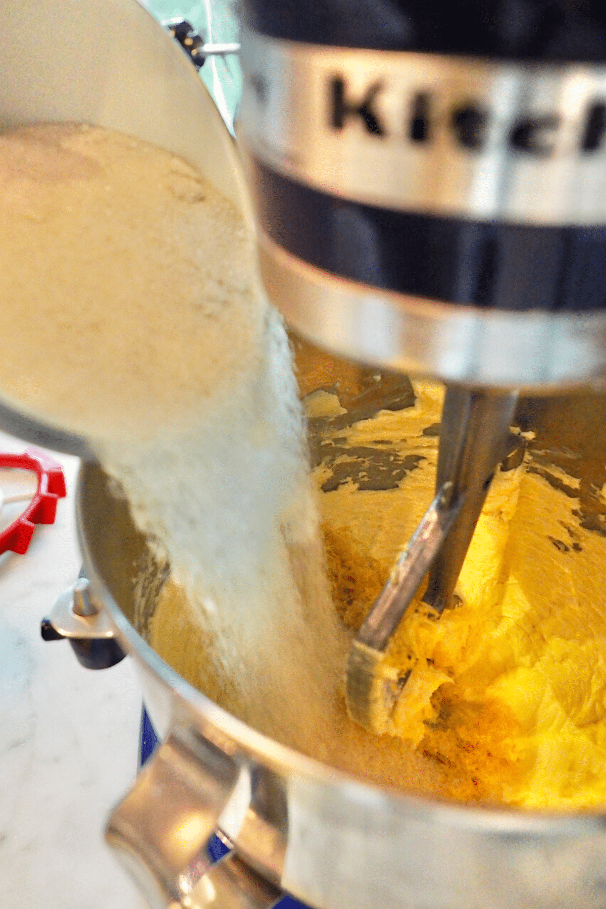 Pouring sugar into the creamed butter for lemon bundt cake. 