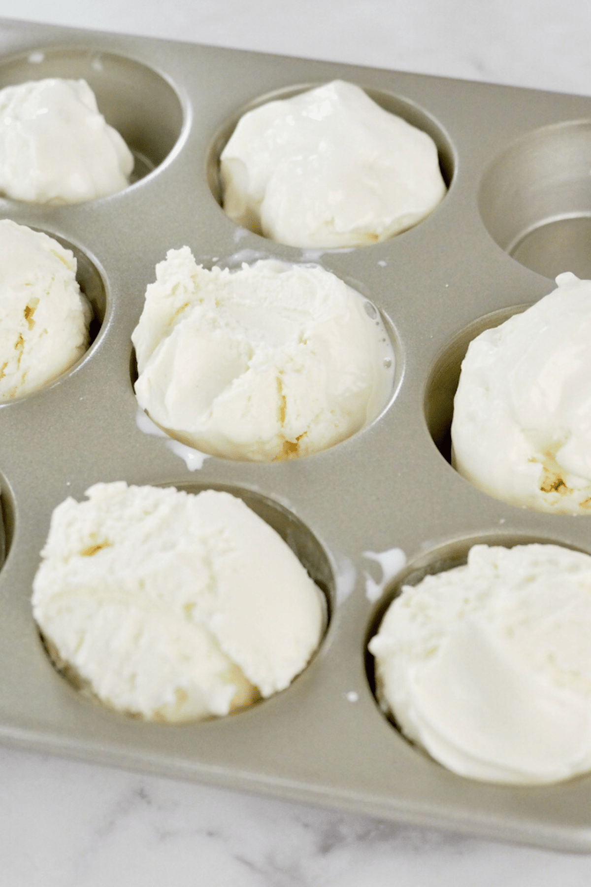 Scooped ice cream balls in muffin tin. 
