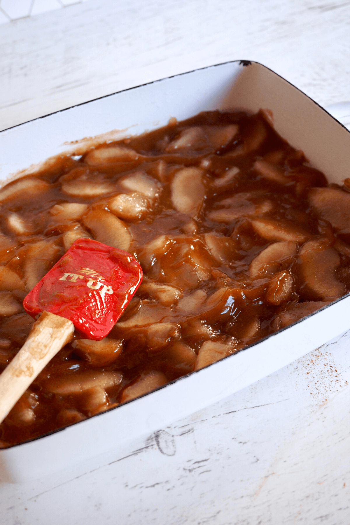 Smoothing apple pie filling mixture in pan. 