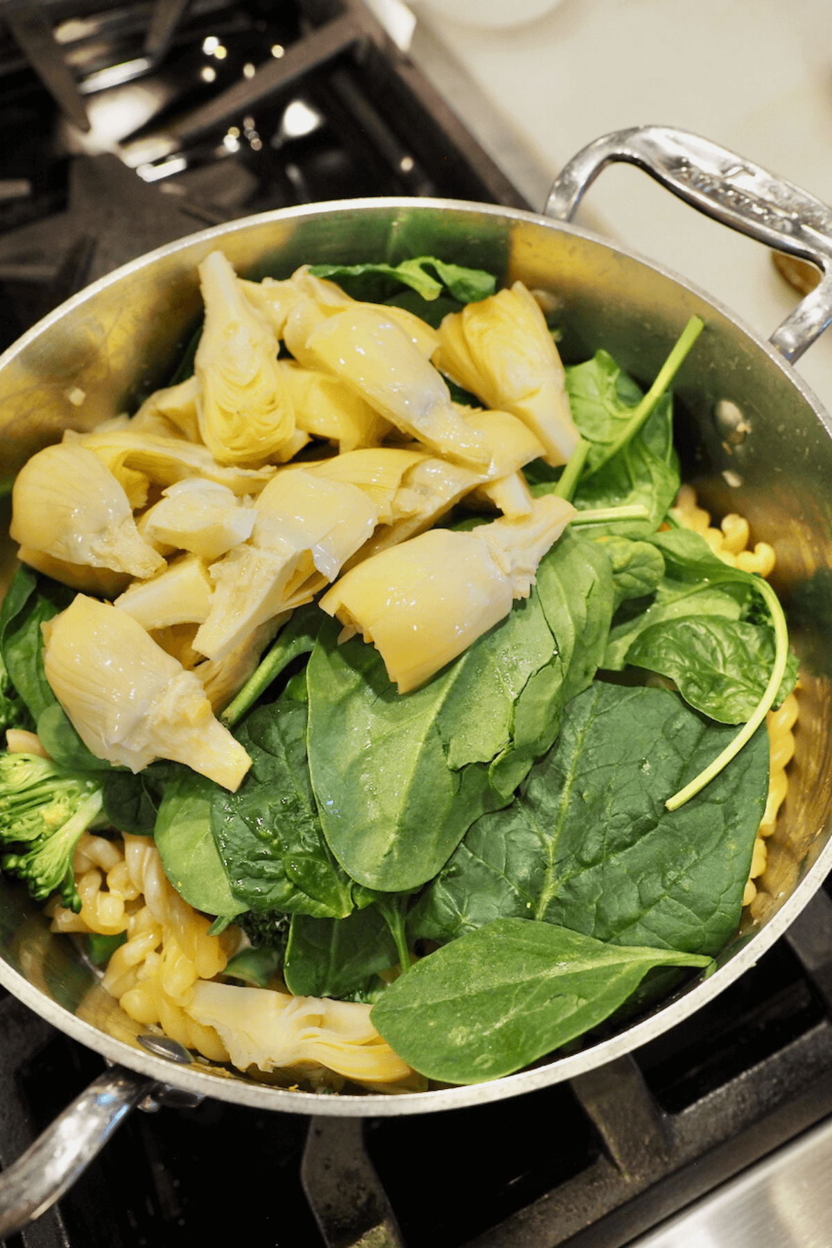 Stir in artichoke hearts and spinach into gemelli pasta recipe. 