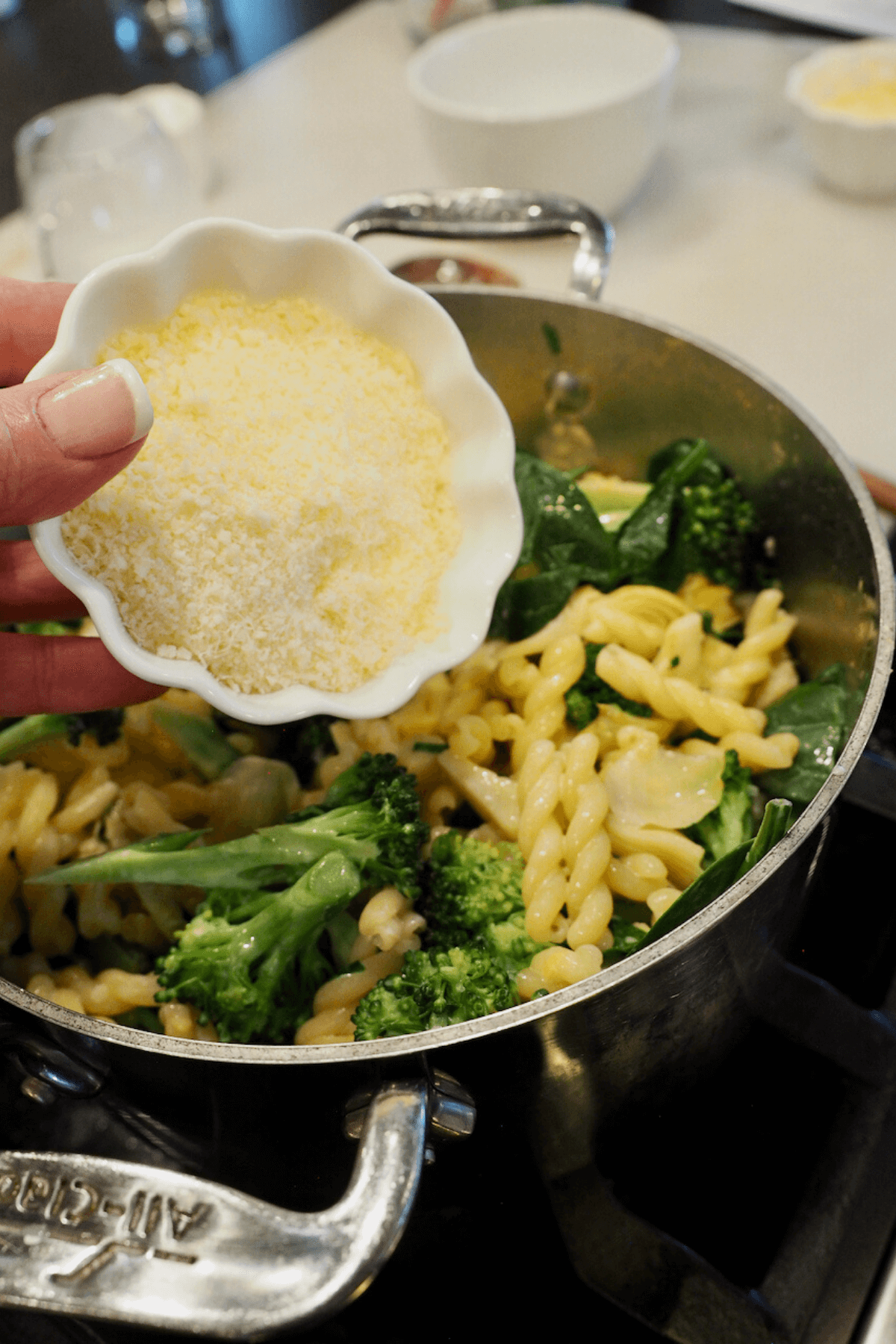 adding parmesan cheese to pasta pot. 