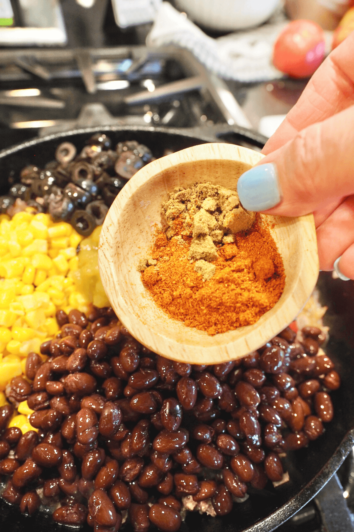 Adding chile powder and cumin to tamale pie mixture. 