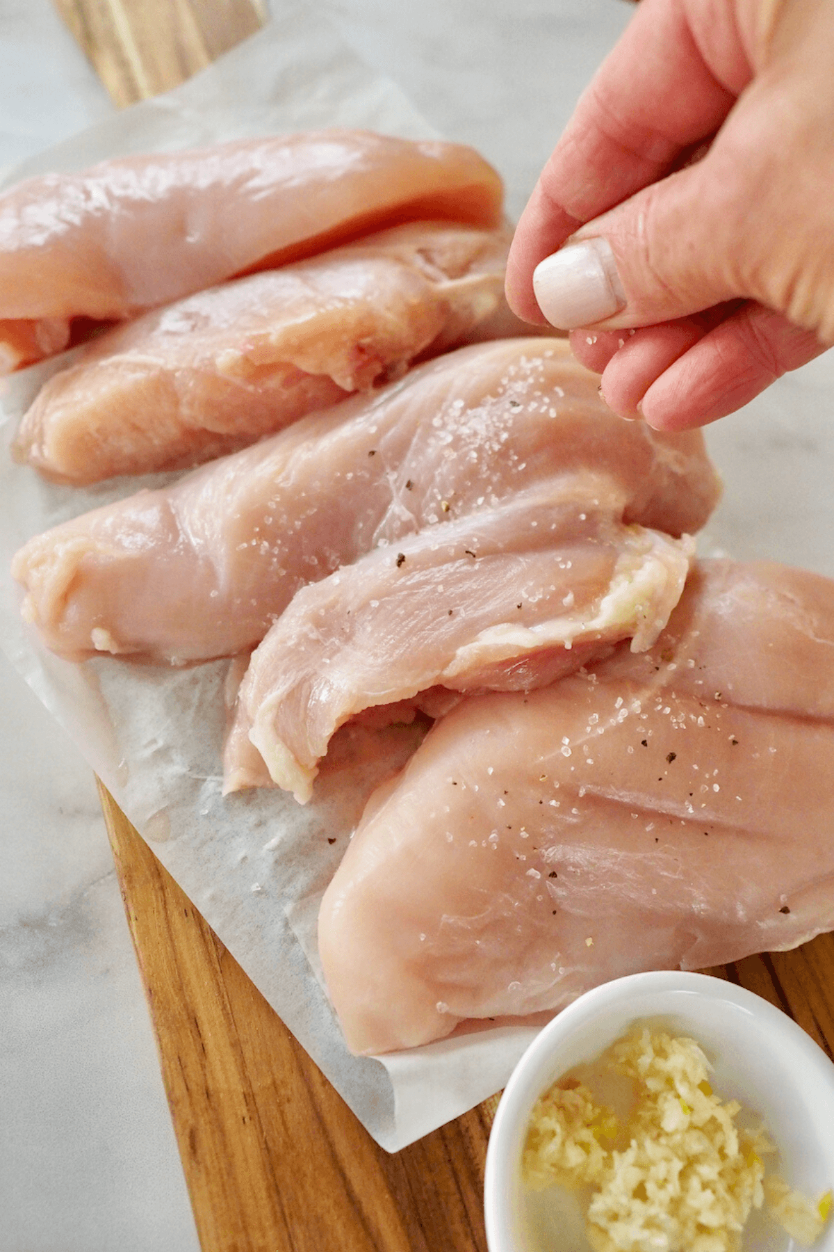 Seasoning chicken breasts with salt, pepper and oregano. 