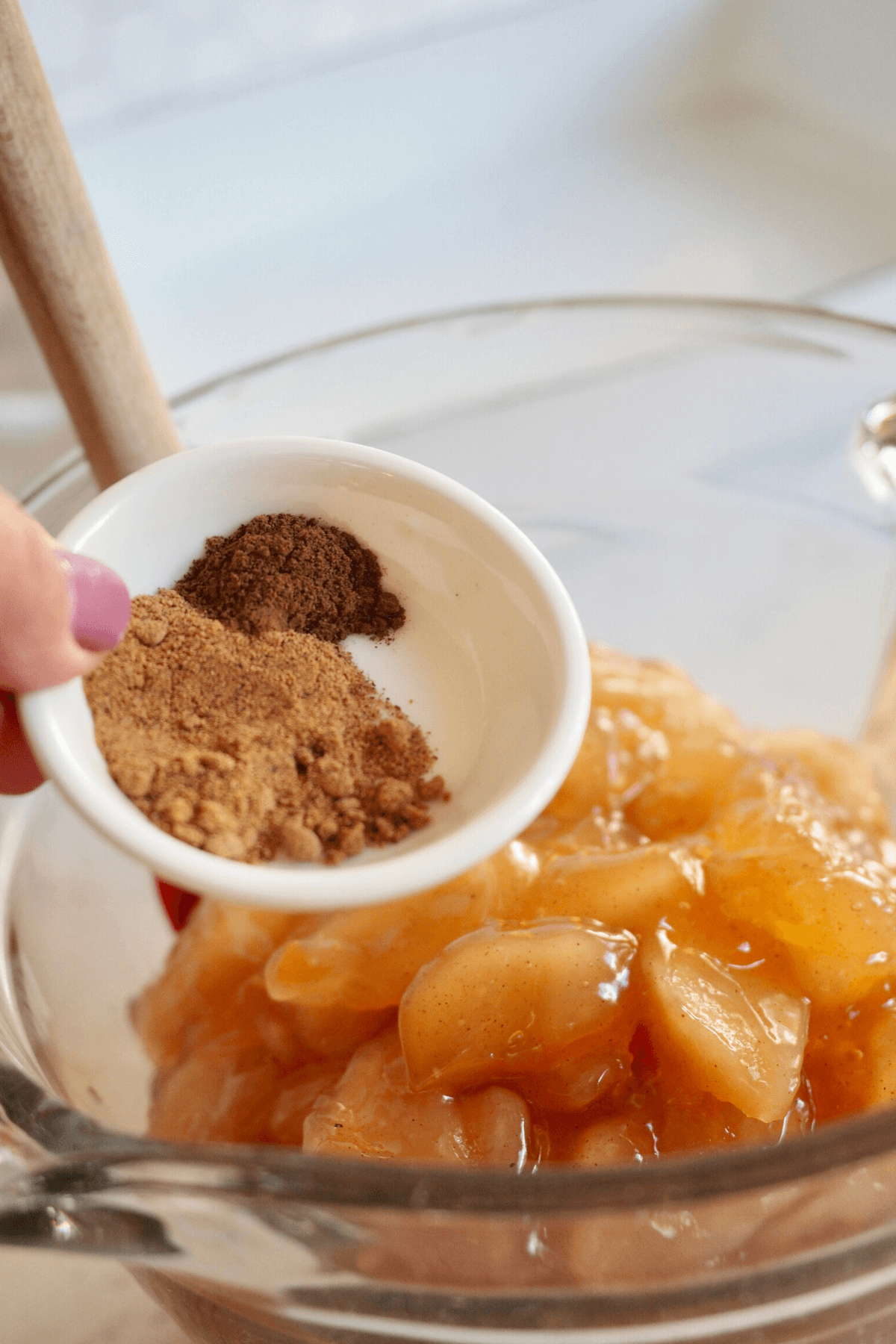 Adding spices to apple pie filling for dump cake recipe.