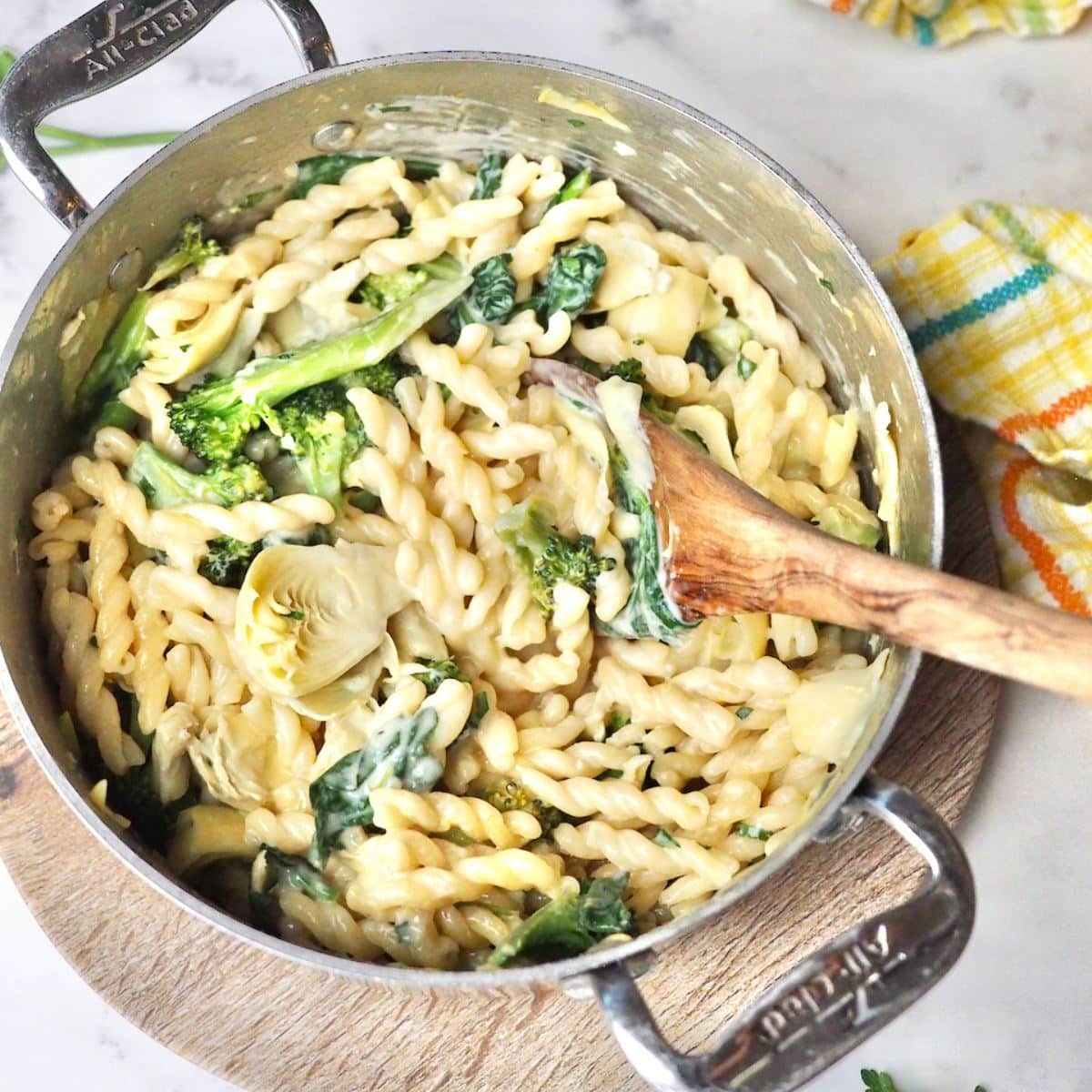Pot filled with on pot creamy garlic lemon pasta recipe with wooden spoon to serve.