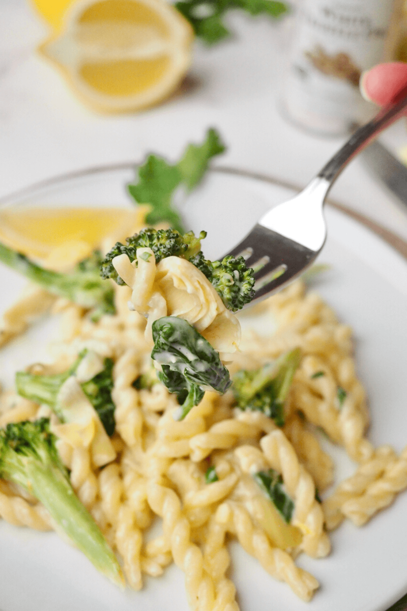 Gemelli pasta recipe with hand holding forkful of pasta.