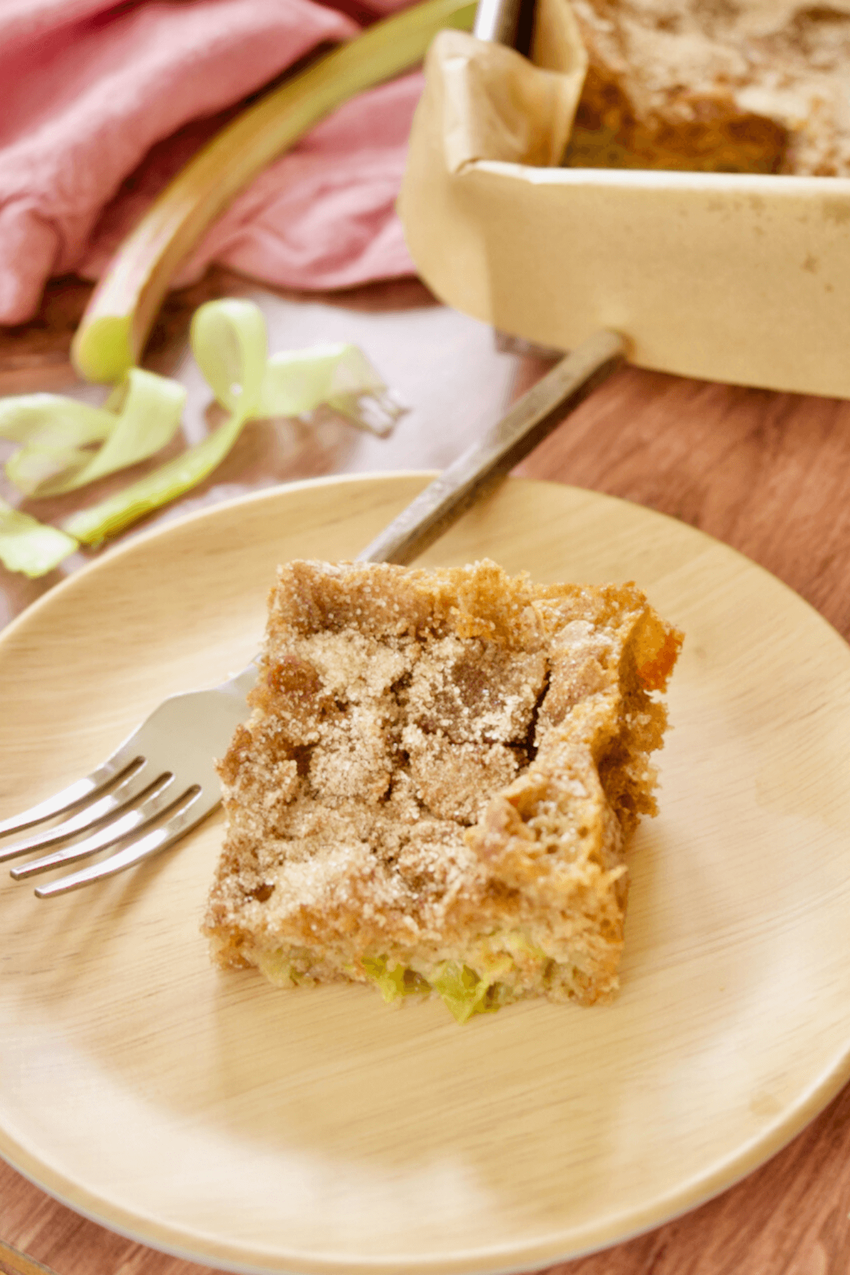 Slice of rhubarb coffee cake on plate with rustic fork.