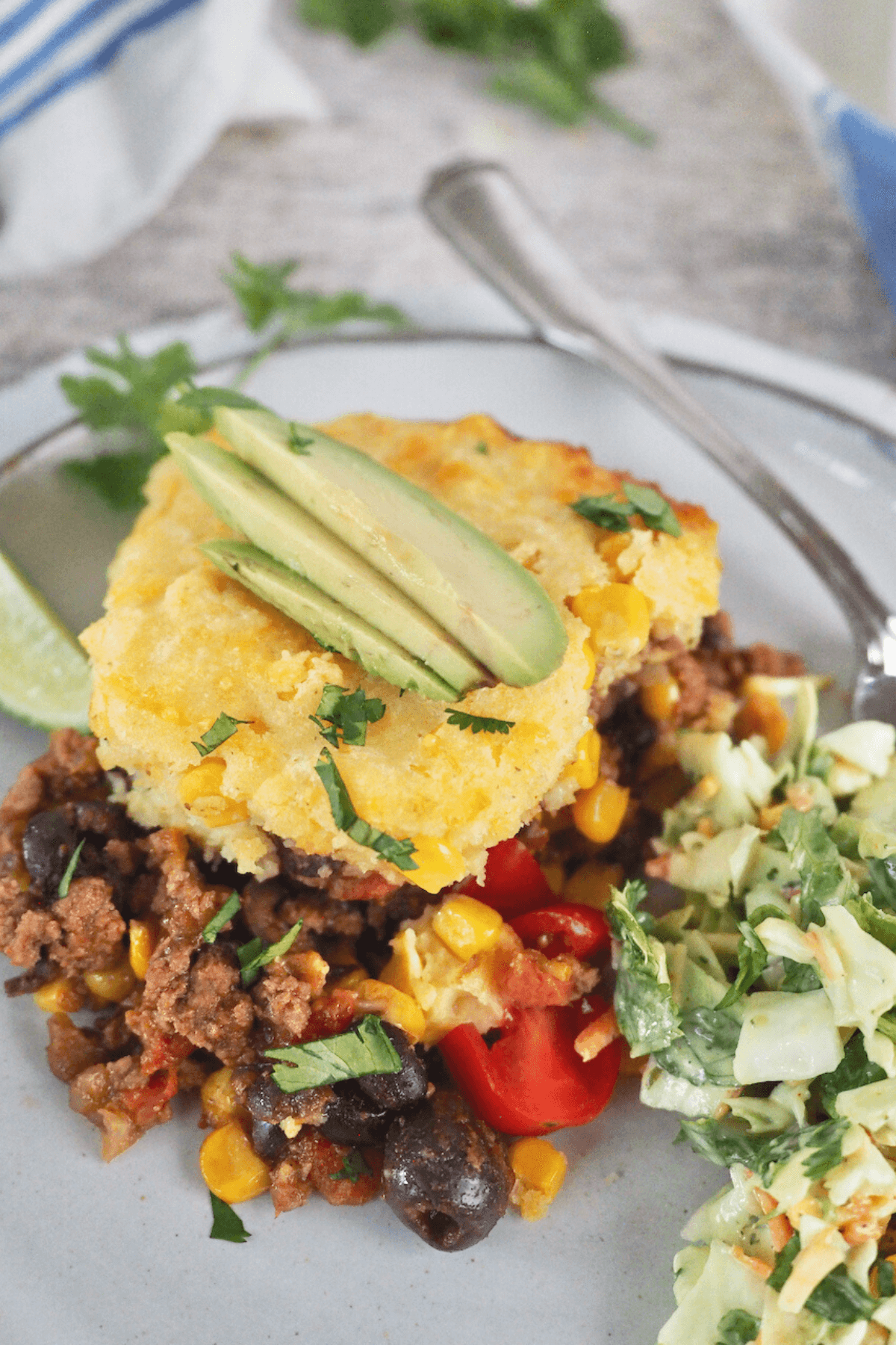 Best tamale pie recipe with serving on a plate garnished with salad and avocado.