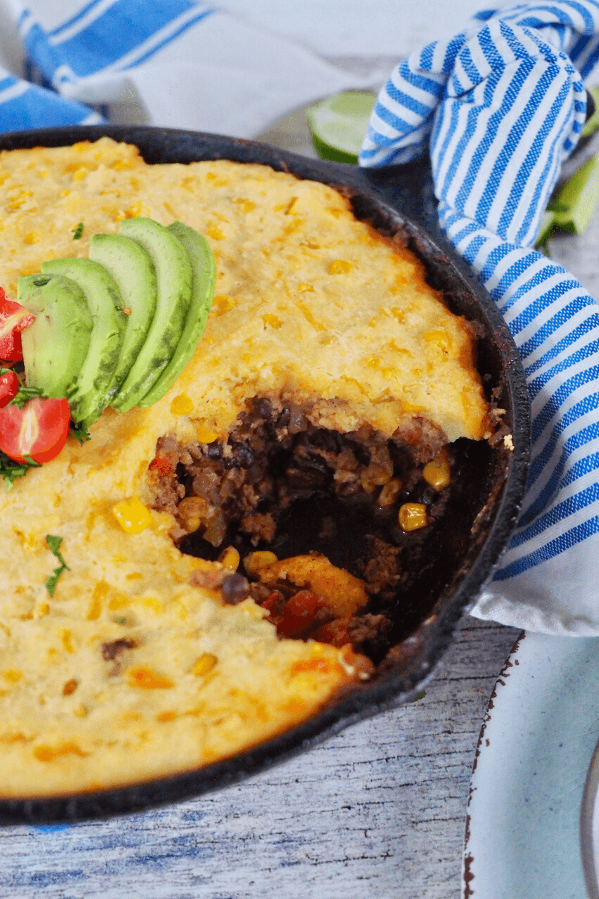Skillet filled with Tamale Pie recipe with cornmeal crust with scoop taken out of it.