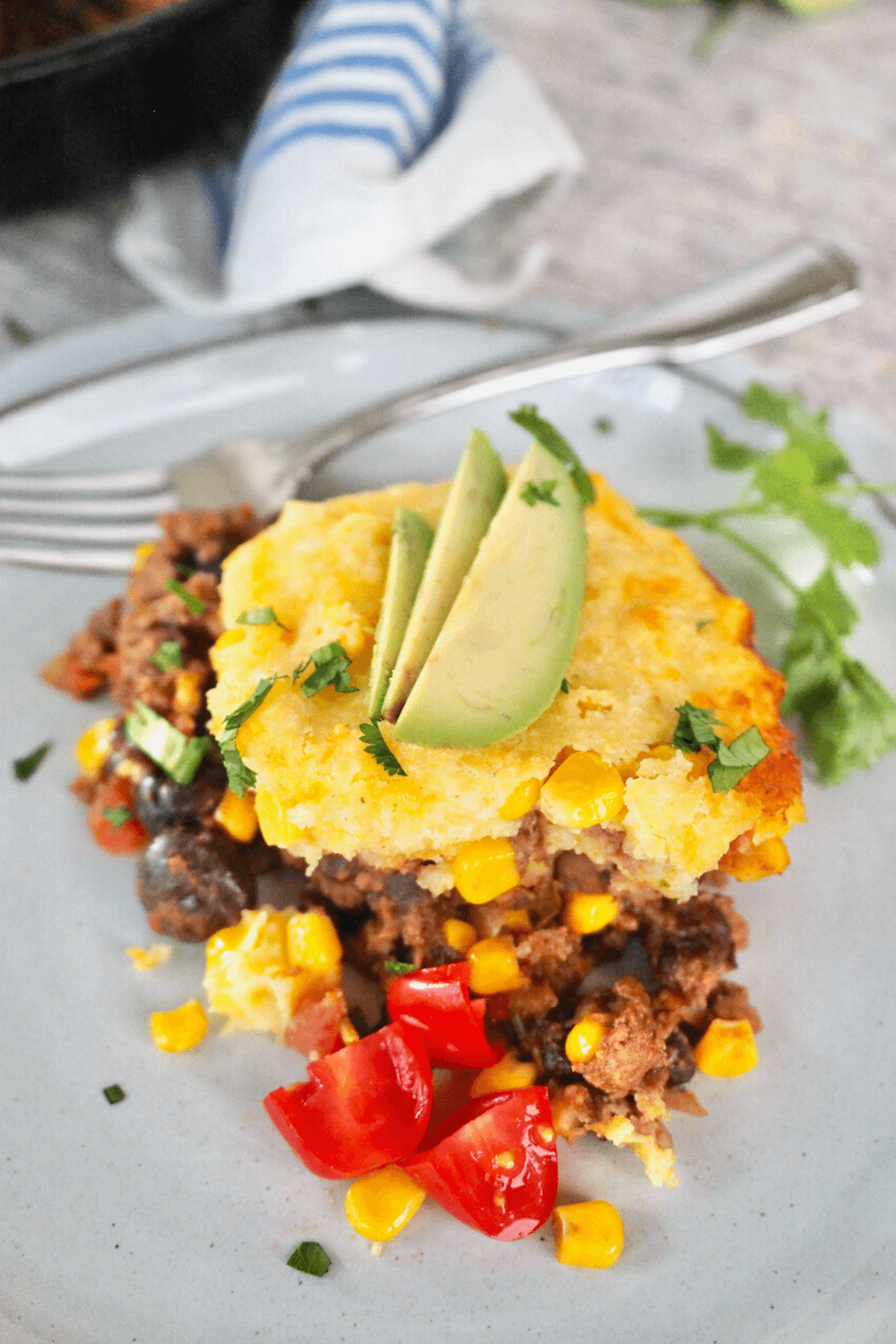 Slice of tamale pie on plate with skillet in background.