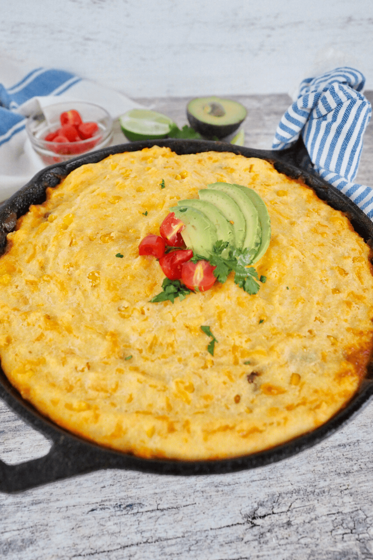 Tamale Pie recipe with cornmeal crust garnished with avocado and chopped tomatoes.