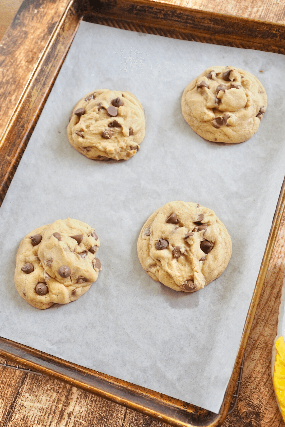 Baked giant Copycat Crumbl Chocolate Chip Cookies on baking sheet cooling.
