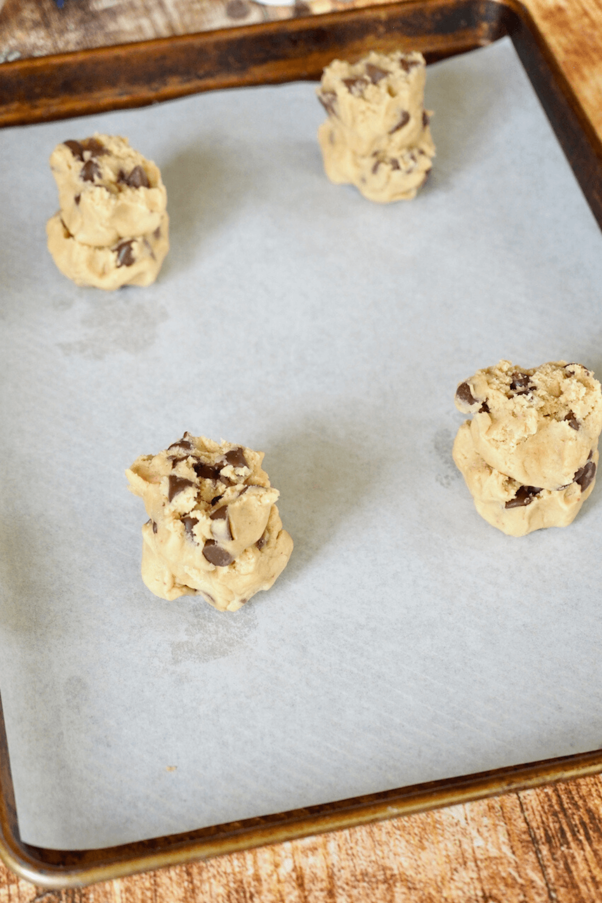 Crumbl chocolate chip cookie dough balls on baking sheet.