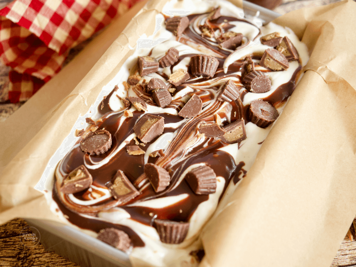 Moose tracks ice cream in pan, with swirls of chocolate and peanut butter cups.