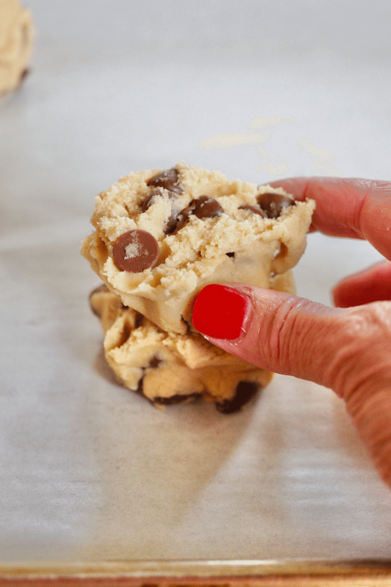 Placing jagged edges of cookie dough half on top of other half for giant Crumbl cookies.