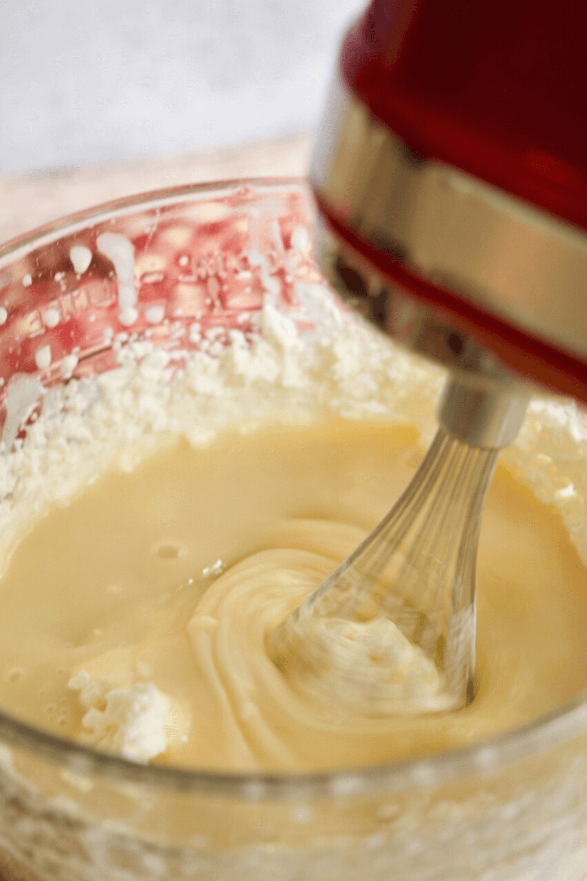 Whipping whipped cream and sweetened condensed milk in bowl with hand mixer.