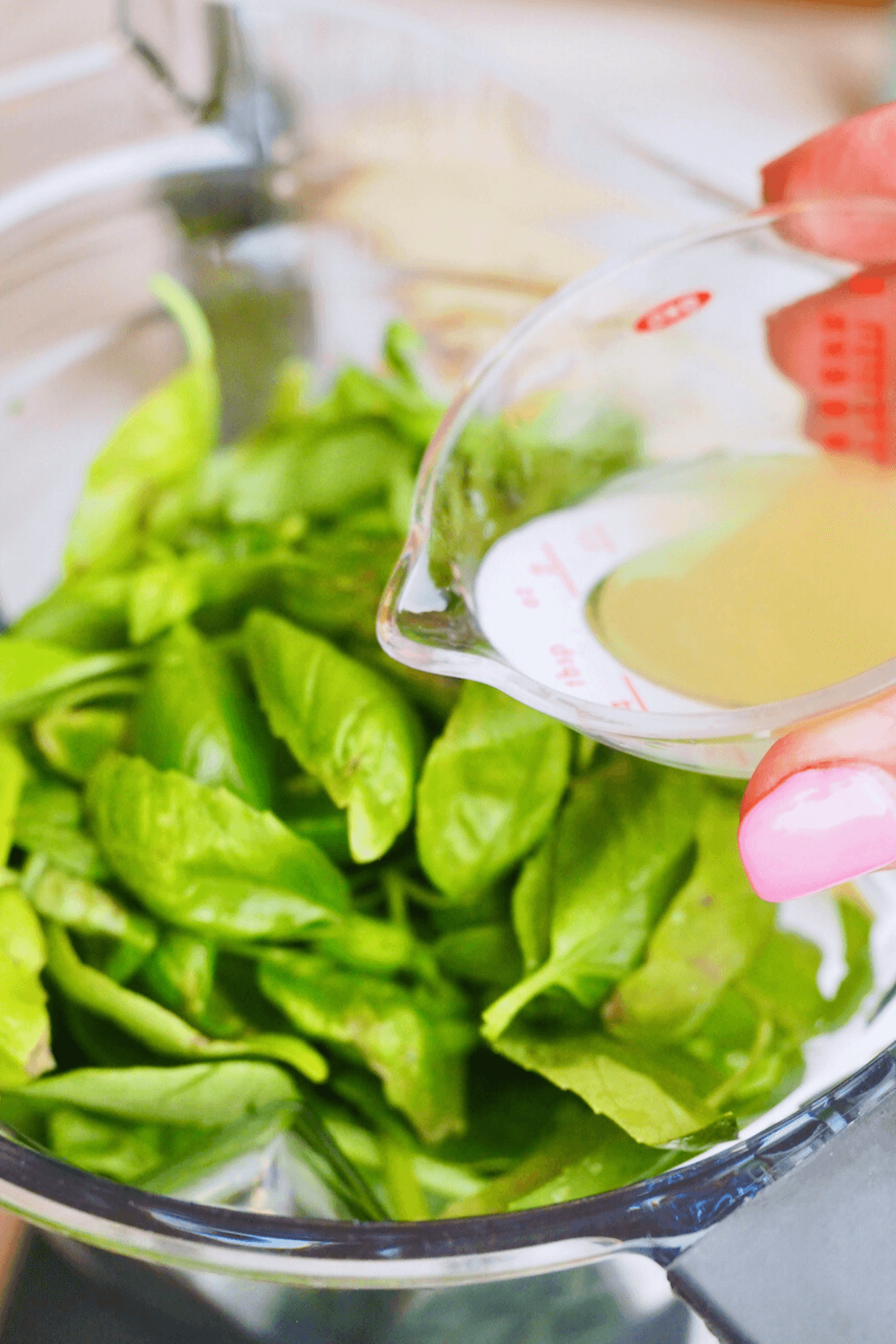 Adding lemon juice to basil and spinach leaves in blender.