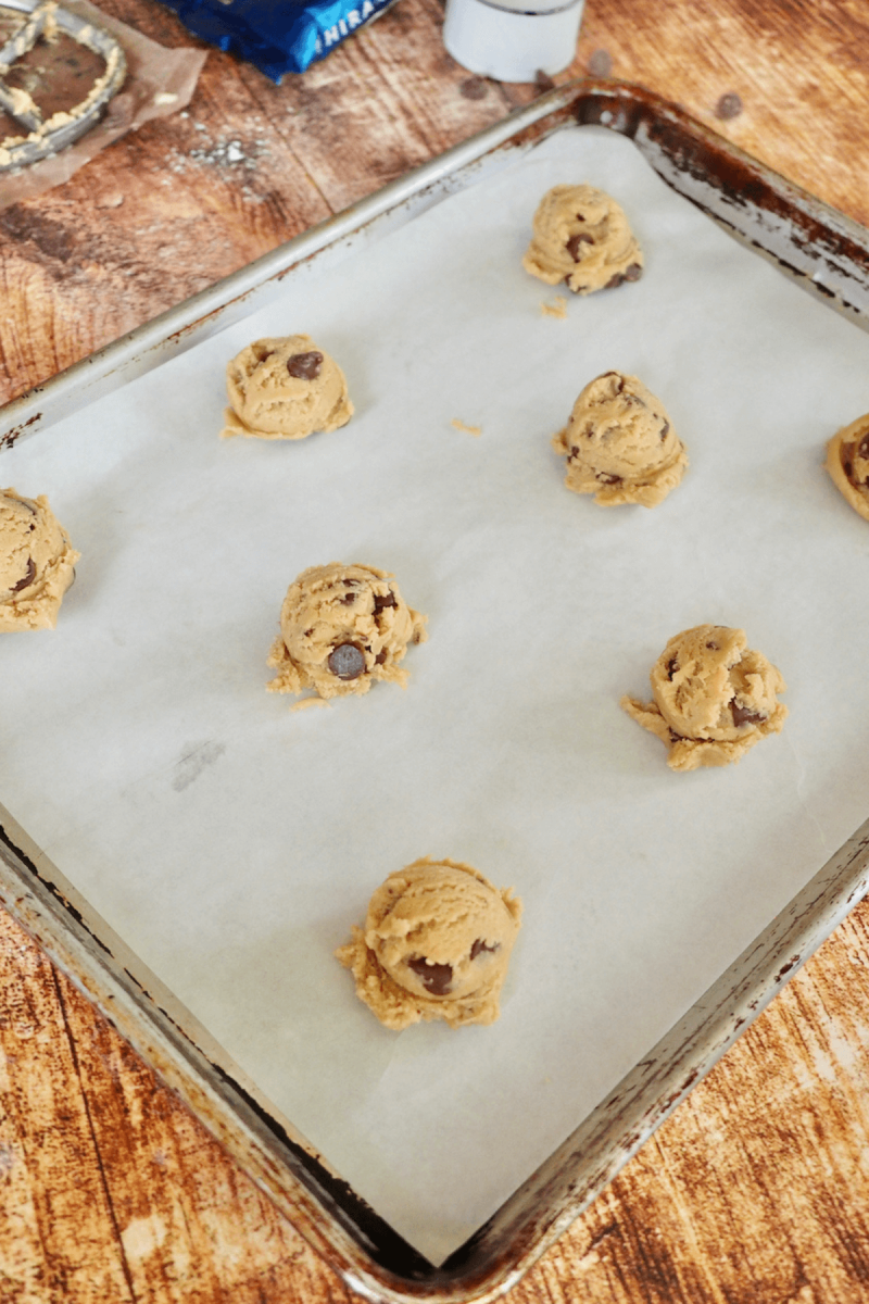 Regular sized or mini crumbl cookie dough on parchment lined baking sheet.