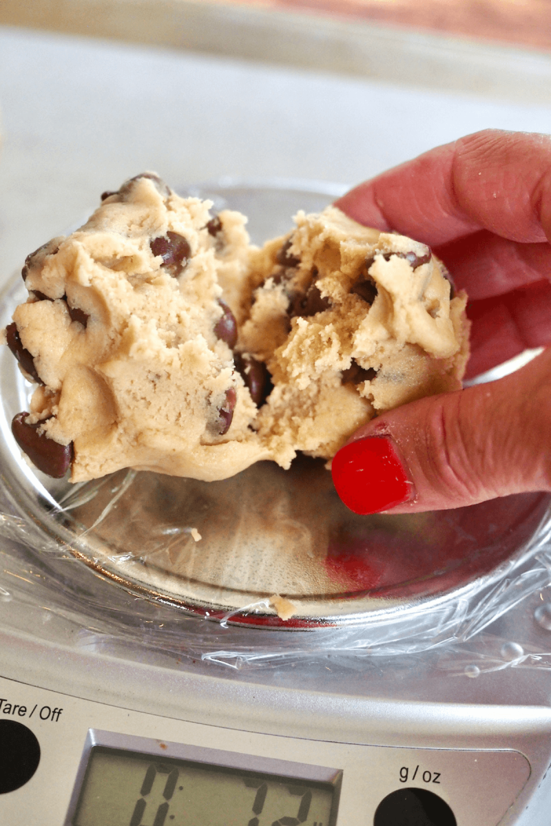 Pinching cookie dough ball in half for baking. 
