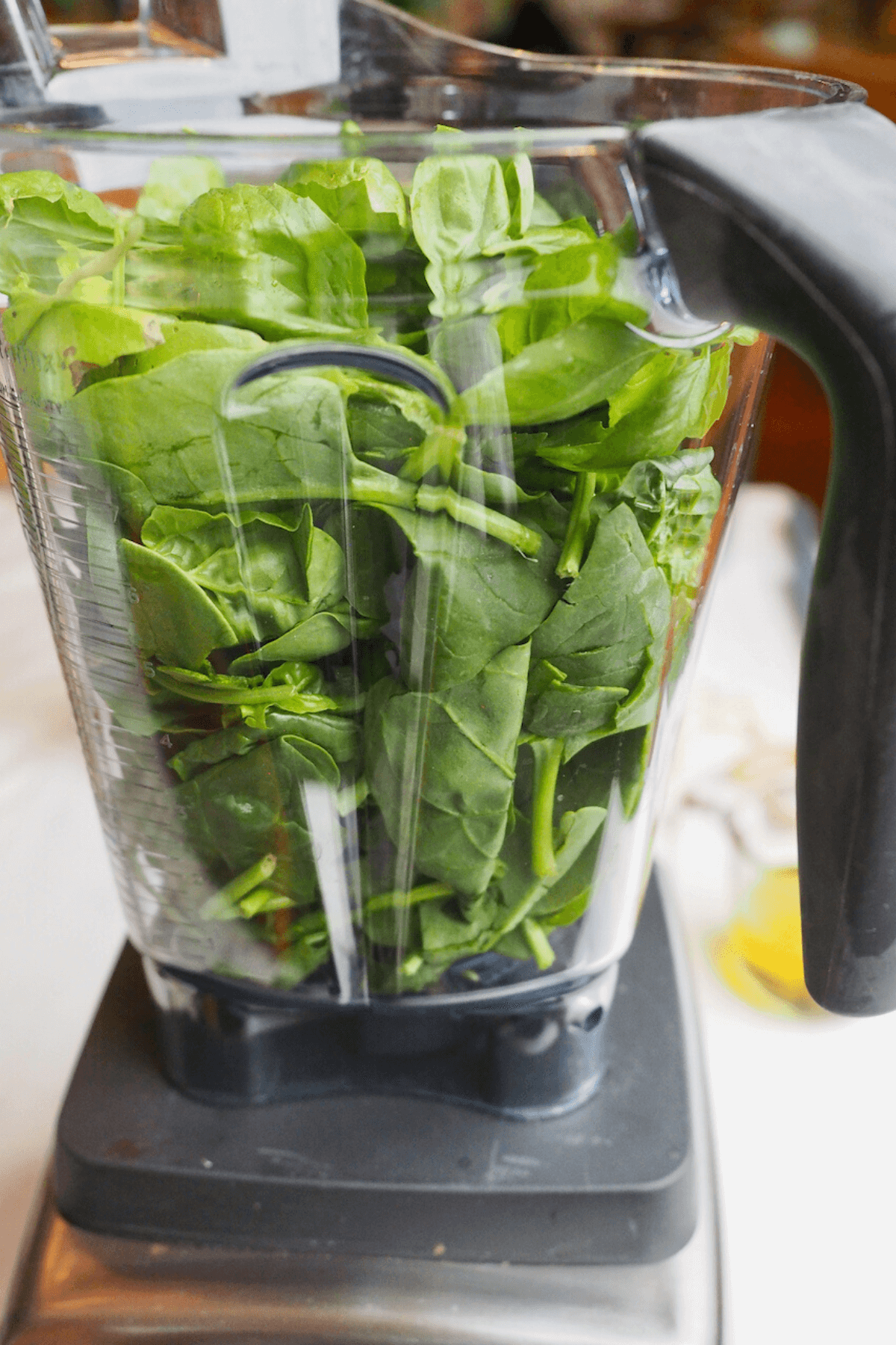 Spinach and pesto added to blender or food processor. 