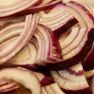 Sliced red onions on a cutting board.