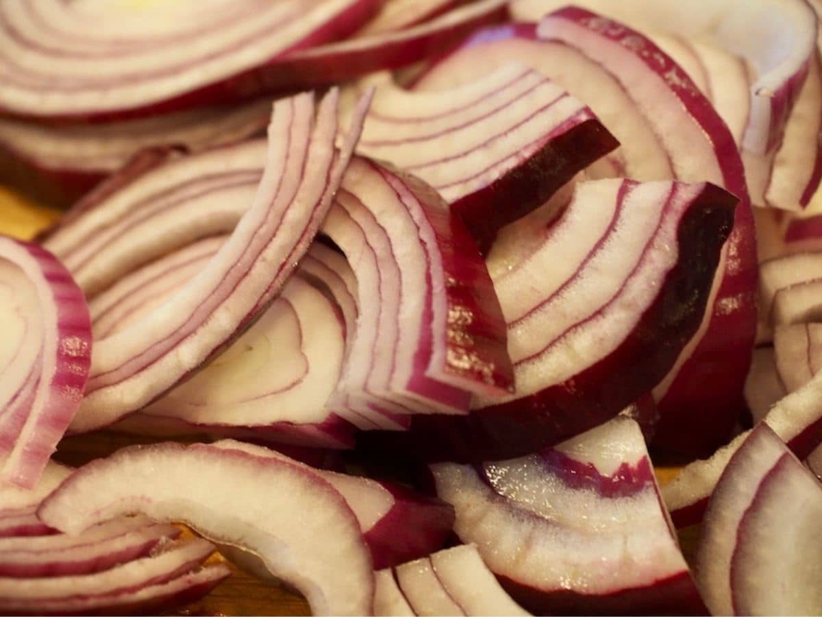 Sliced red onions on a cutting board.