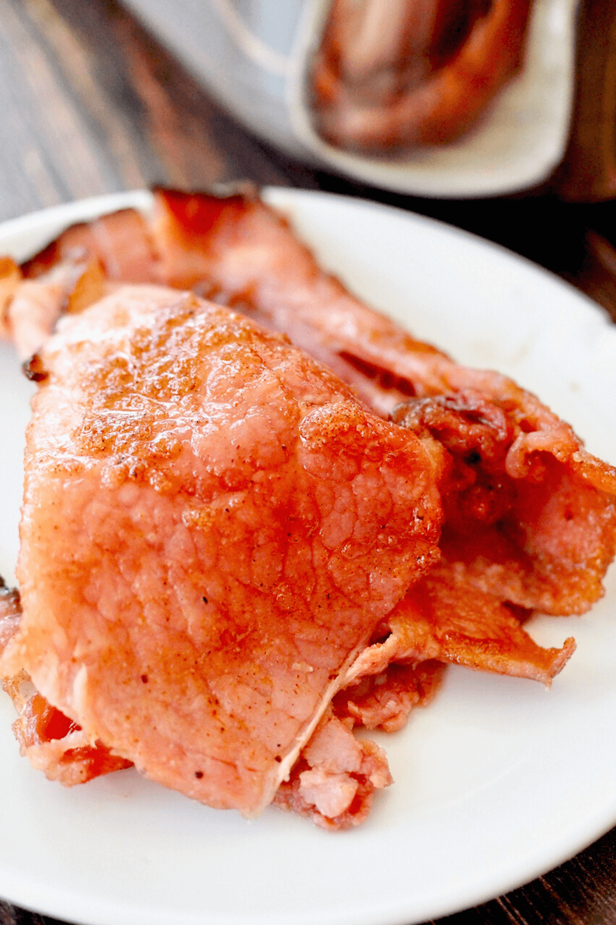 Slices on plate of honey baked ham with sugary and crispy crust.