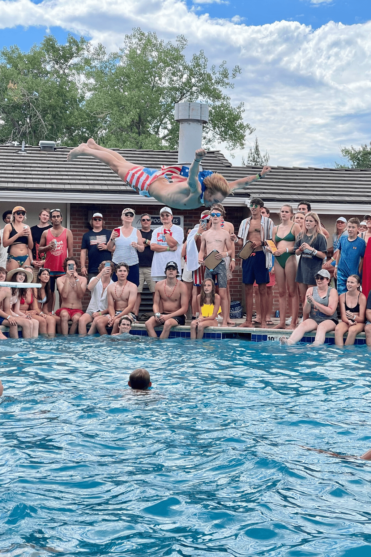 belly flop contest, man dressed in red, white and Blue mid air above pool.