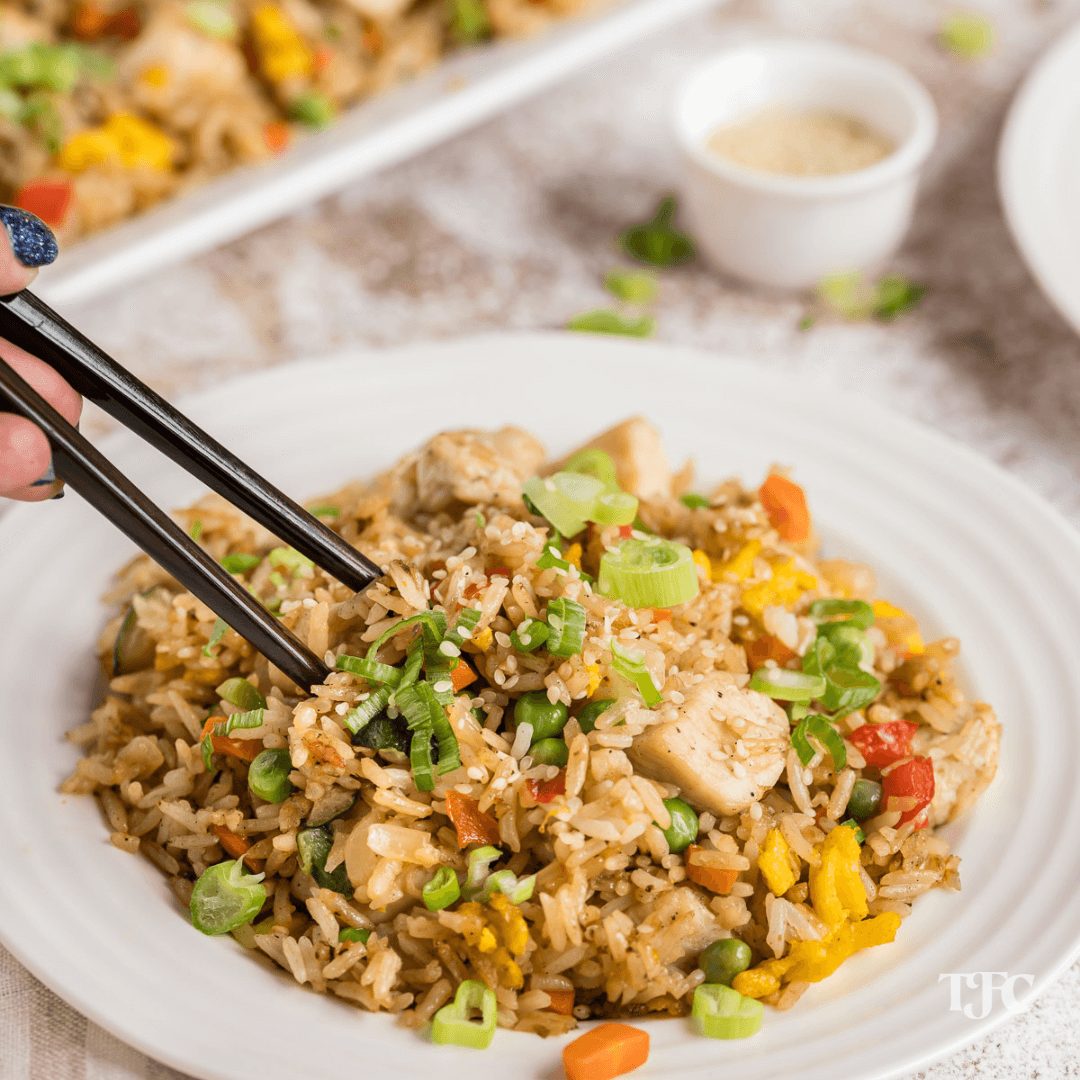 Blackstone Chicken Fried Rice with chopsticks and hand taking a bite.