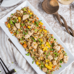 Blackstone Chicken Fried Rice Recipe top down shot with platter filled with chicken fried rice, wooden spoon nearby along with some chop sticks.