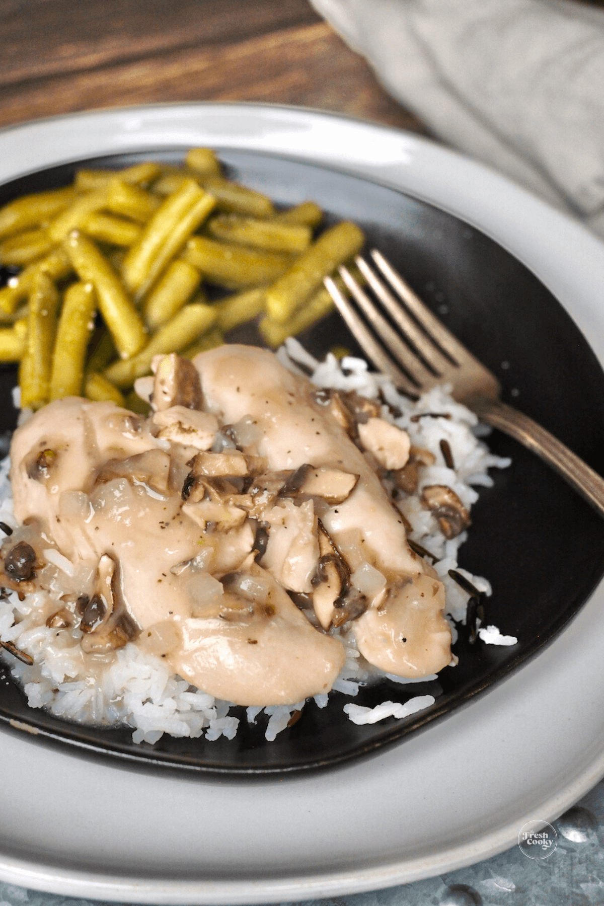 Best Cracker Barrel Chicken and Rice recipe on black plate with green beans and a pretty fork on the side.