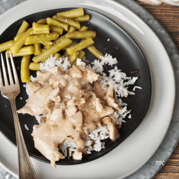 Cracker Barrel Chicken and Rice Recipe on black plate with cream charger and silver fork, served with green beans.