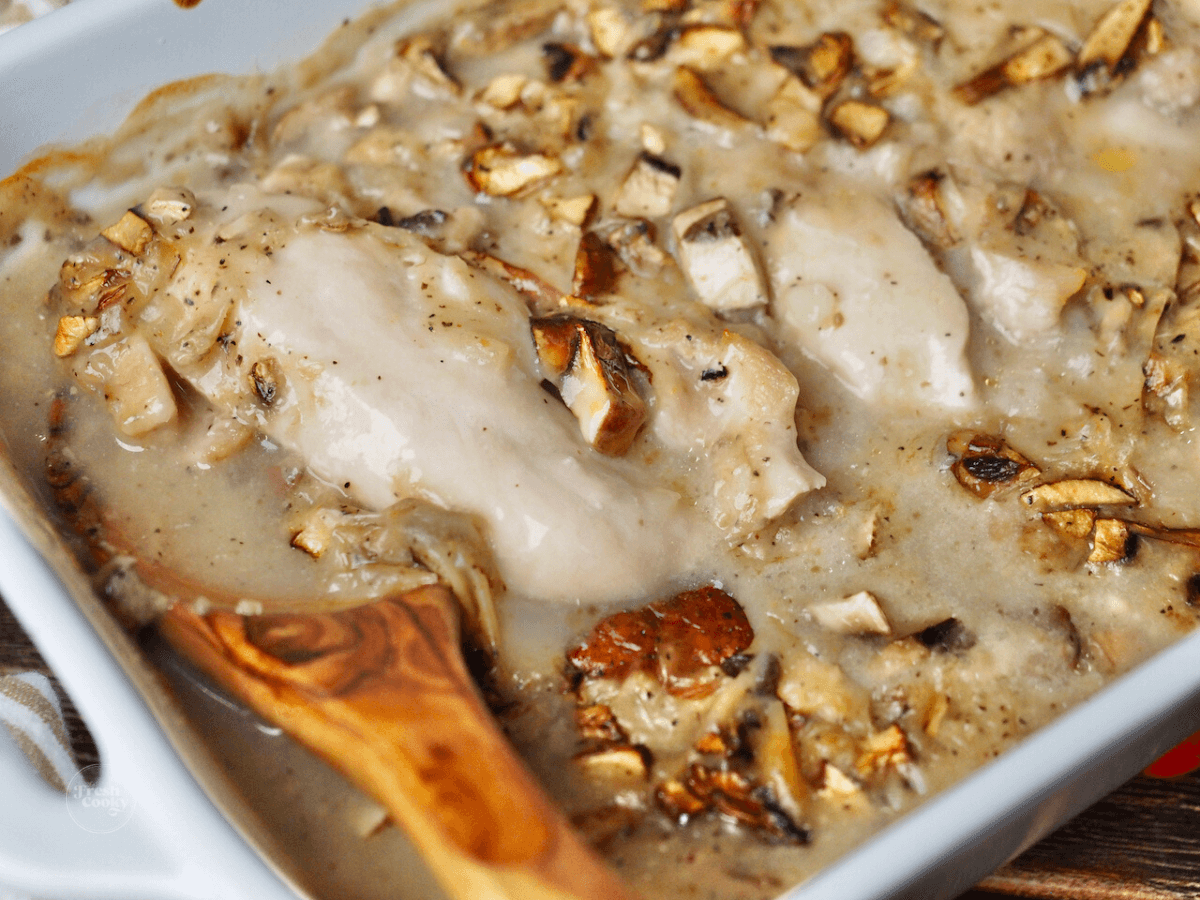 Cracker Barrel Chicken and Rice Recipe with wooden spoon in casserole dish, spooning out chicken and gravy.