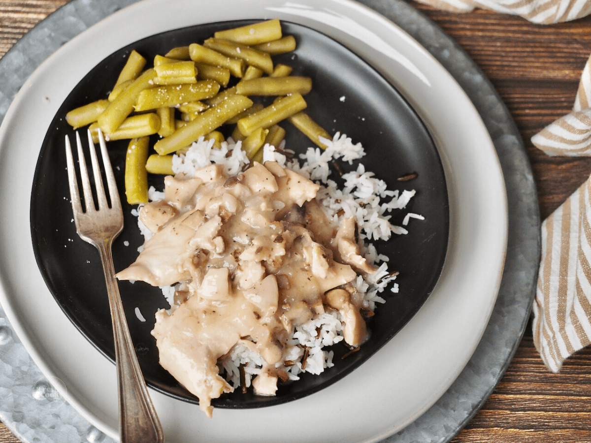chicken and rice with gravy and green beans on black plate. 