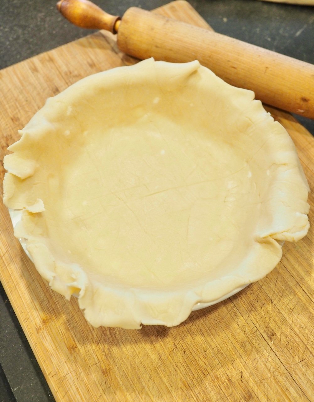 Pie dough rolled into pie plate with rolling pin. 
