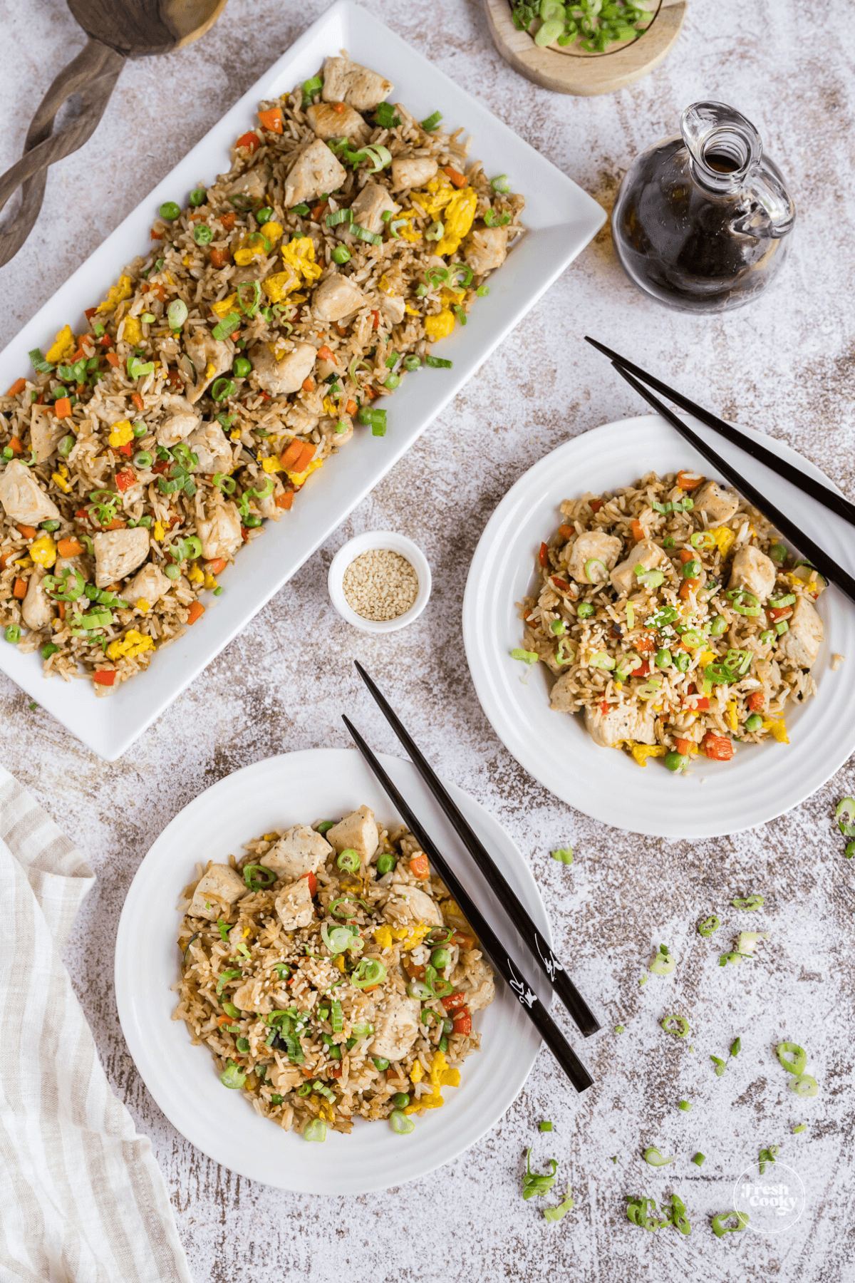 Blackstone chicken fried rice recipe top down shot with two plates filled with fried rice, and black chopsticks on the side, with serving platter with the rest of the rice.