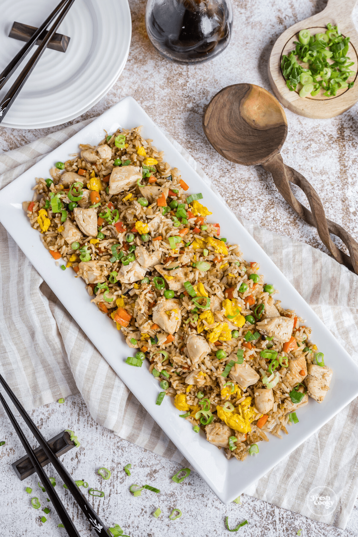 Best Blackstone Chicken Fried Rice Recipe in pretty rectangular dish with wooden spoon and chopsticks nearby.