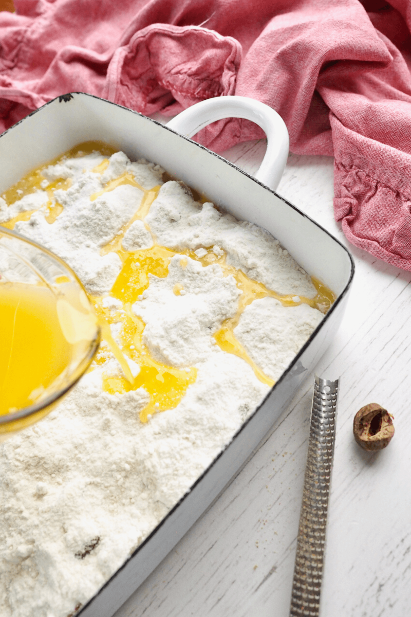 Pouring melted butter over the top of rhubarb dump cake.