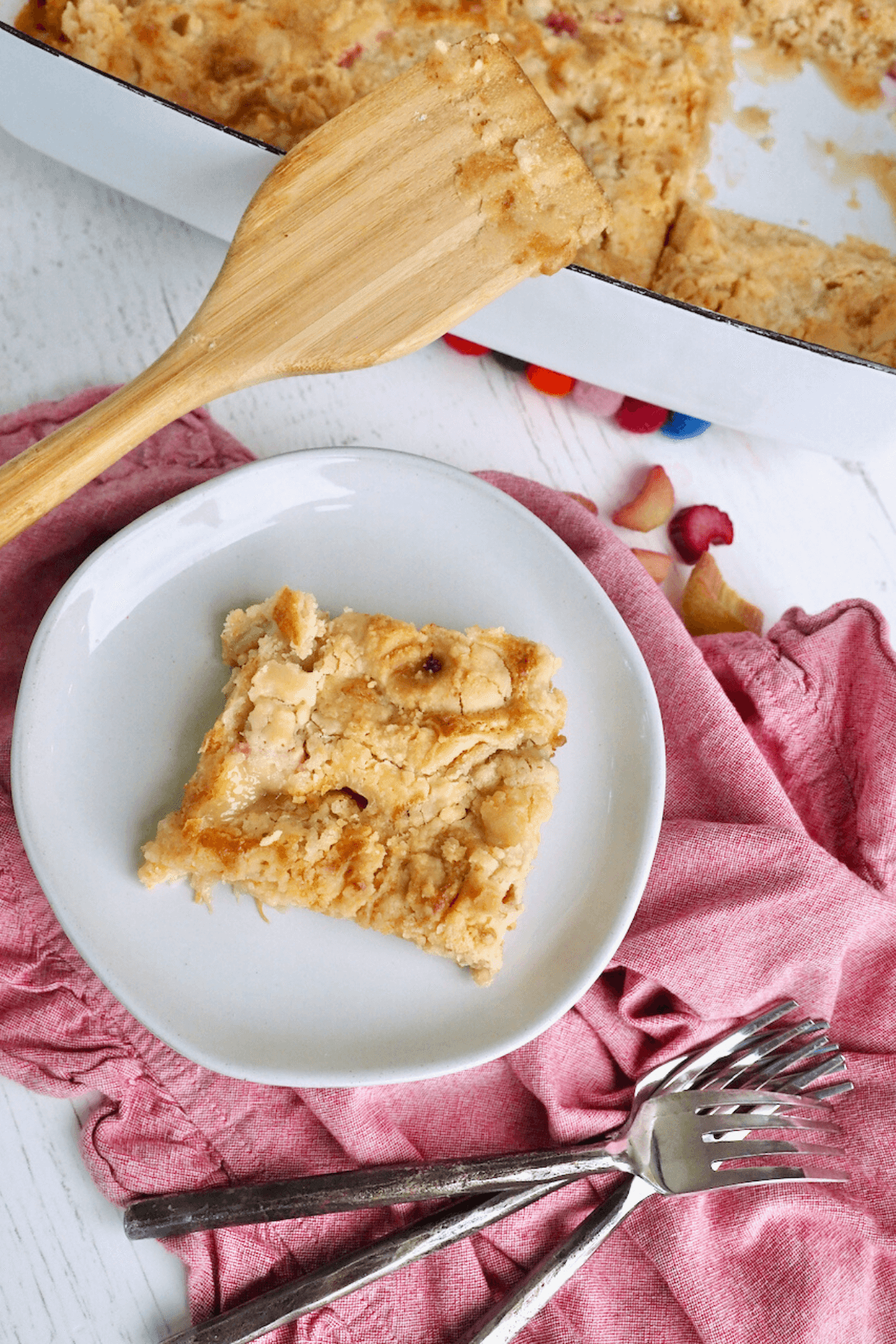 Rhubarb dup cake sliced and on plate with forks and the baking dish in the back ground.