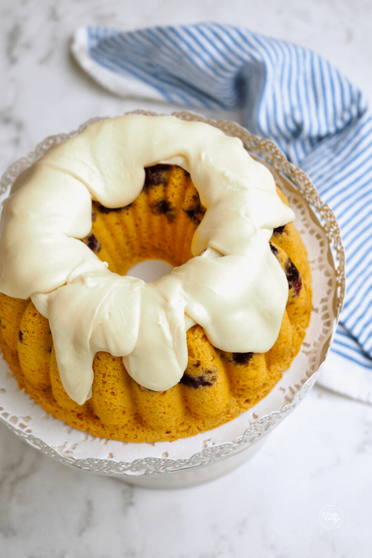 Blueberry Pancake Bundt Cake recipe with whole cake on pedestal drizzled with maple glaze.