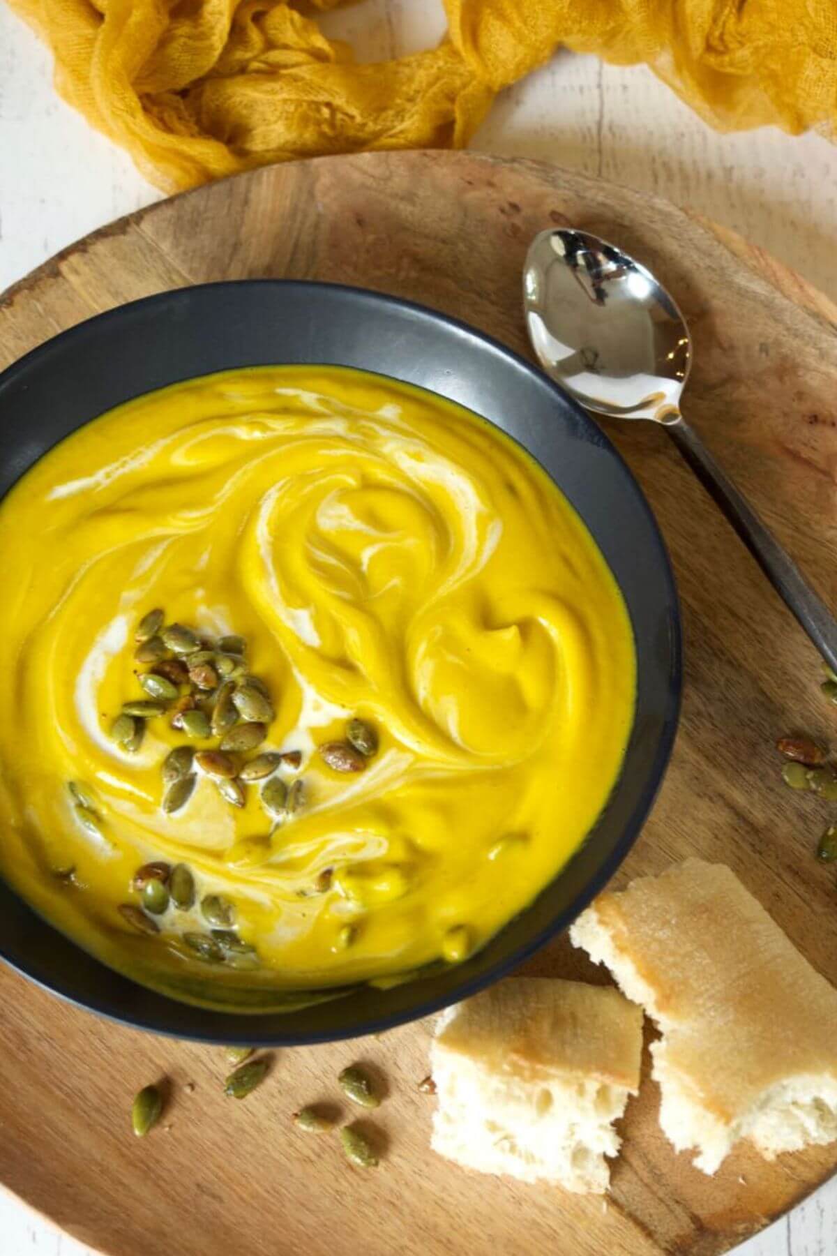 Panera autumn squash soup recipe serving in a black bowl with French bread and a spoon,
