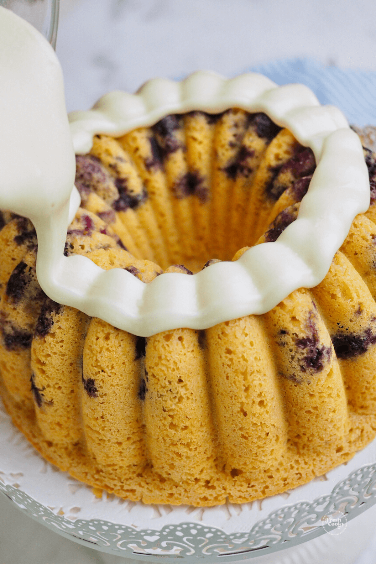 Pouring a thick ring of maple butter glaze on top of the blueberry buttermilk bundt cake. 