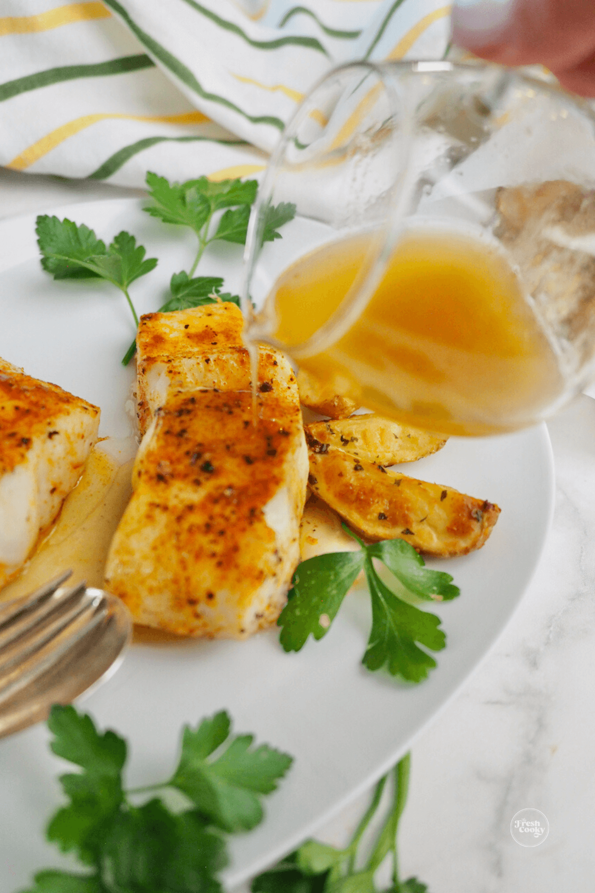 Pouring lemon butter sauce on halibut filets.