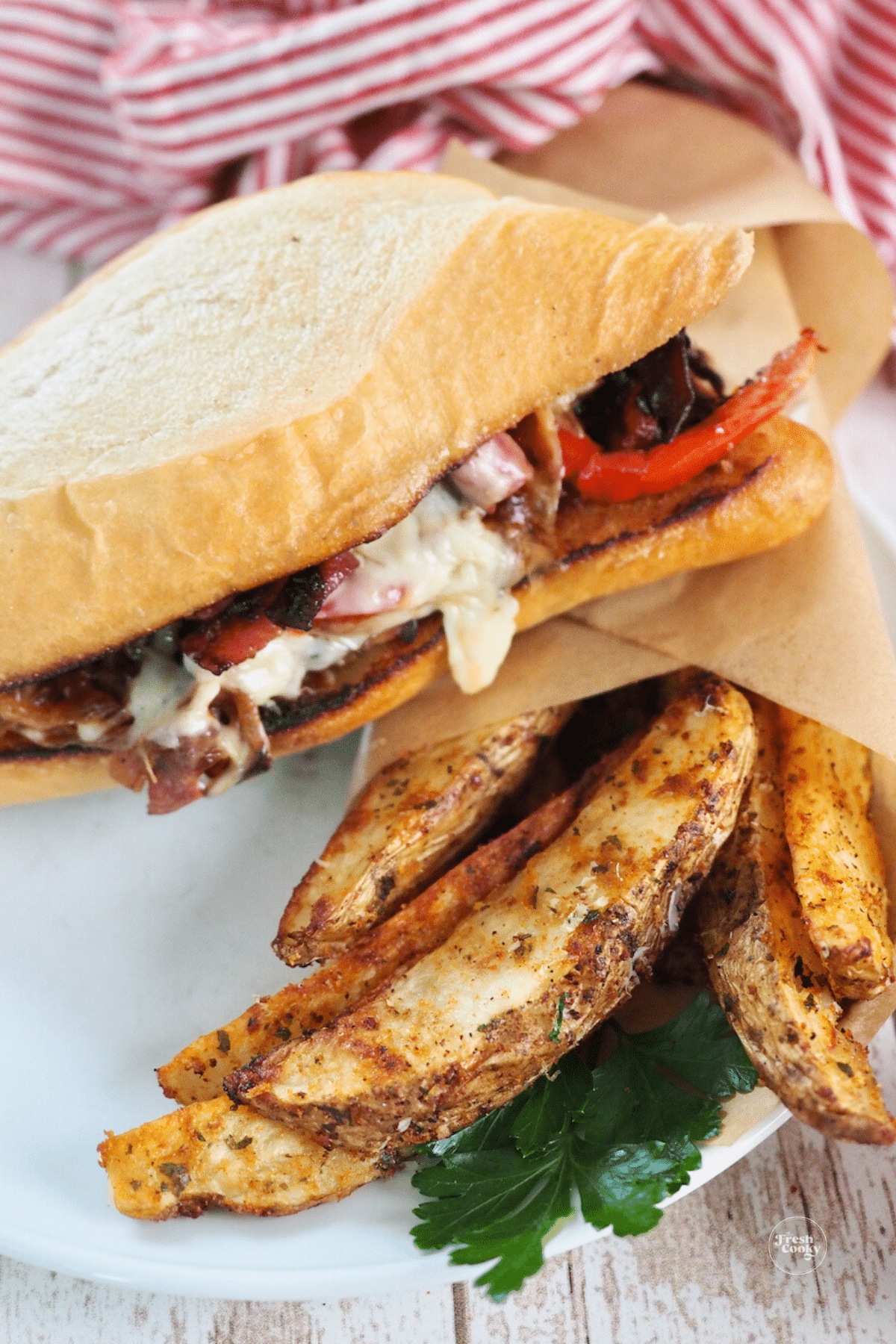 Steak sandwich on plate with steak fries, serving suggestion.