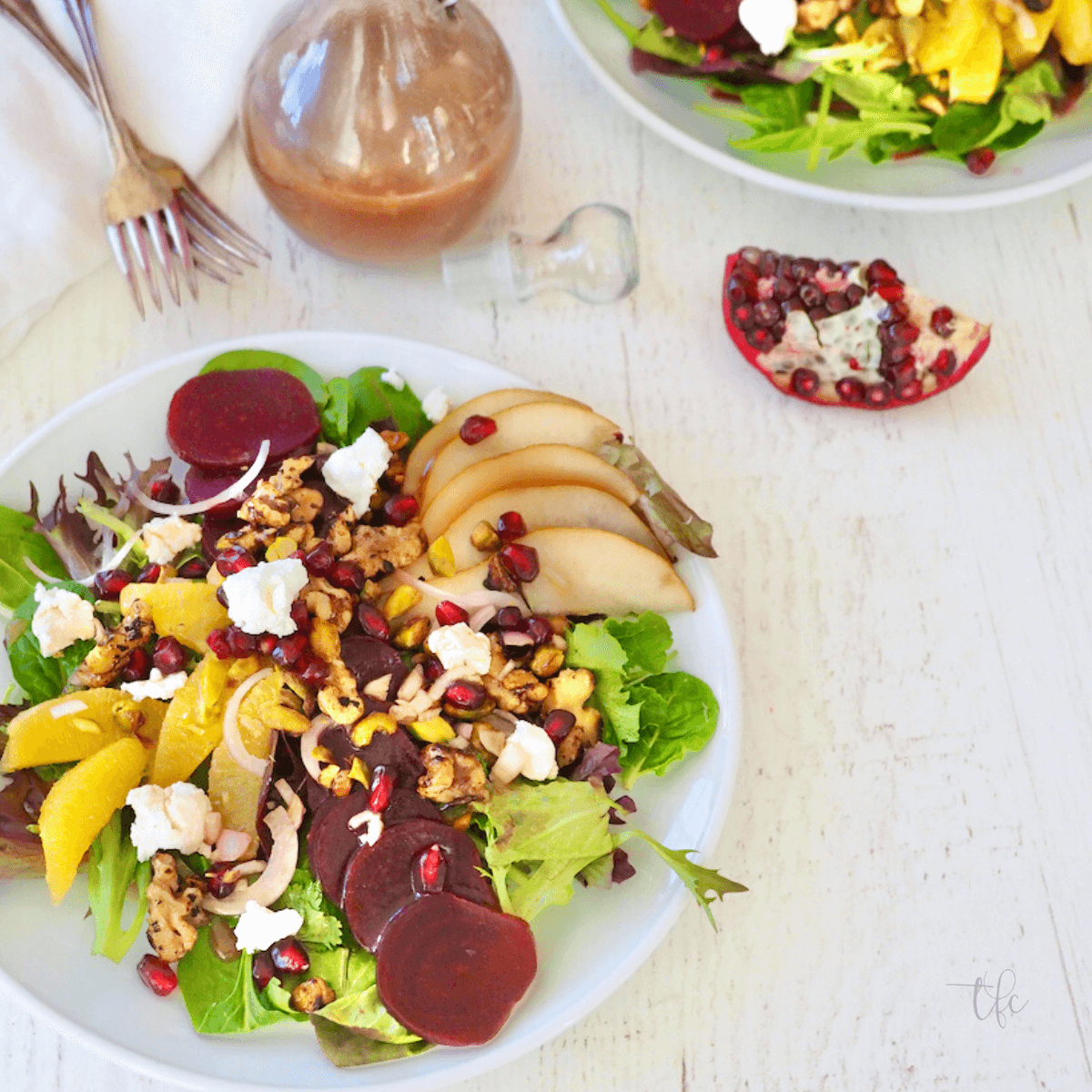 Plated salad loaded with beets and fruit with pomegranate dressing.