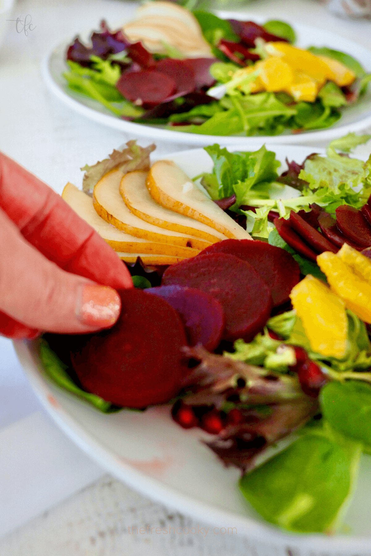 Adding sliced beets to salad plate. 